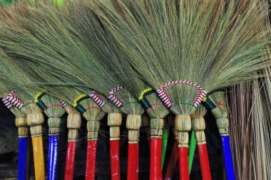 Artisanal hand made modern tiger grass or walis tambo-soft brooms with colored handles standing for sale in a stall at the Central Public Market. Bacolod-Negros Occidental-Wester Visayas-Philippines. clipart
