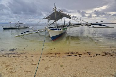 Punta Ballo sahilinde karaya oturmuş dalış ve şnorkelle yüzme merkezlerinin turistik kullanımı için dengeleyici ya da bangka çift kanatlı tekneler. Sipalay-Zenciler Batı Visayas-Filipinler