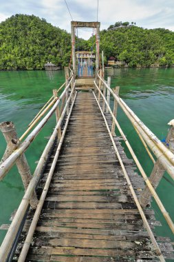 Bambu köprüsü ve ahşap kalaslarla Latasan ve Tinagong Dagat adalarını birbirine bağlayan ağaç korkulukları ve bayraklar. Sipalay-Zenciler Batı Visayas-Filipinler.
