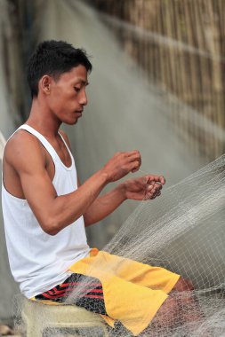 Sipalay, Filipinler-13 Ekim 2016: Balıkçı, Panaon nehir ağzındaki liman bölgesinde bir sonraki sefere hazırlanmak için ağları onarıyor. Zenciler Batı-Batı Visayaları.