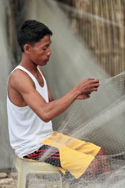 Sipalay, Filipinler-13 Ekim 2016: Balıkçı, Panaon nehir ağzındaki liman bölgesinde bir sonraki sefere hazırlanmak için ağları onarıyor. Zenciler Batı-Batı Visayaları.