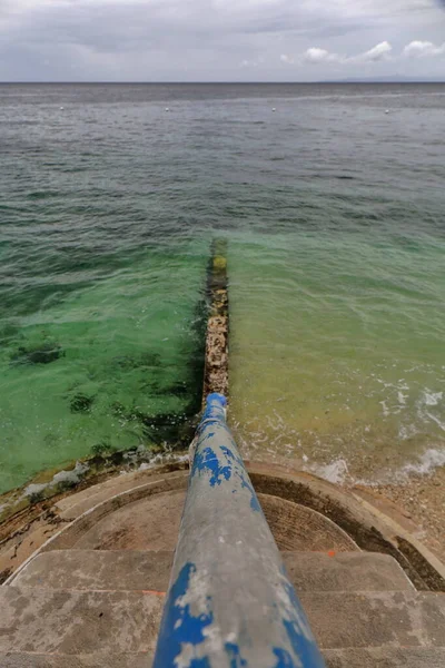 Concrete stairway leading to a low rise jetty covered by the high tide. Coastal area where tourists go to watch whale sharks and snorkel among them which is so invasive. Oslob-Cebu island-Philippines.