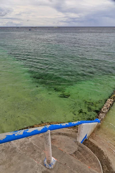 Concrete stairway leading to a low rise jetty covered by the high tide. Coastal area where tourists go to watch whale sharks and snorkel among them which is so invasive. Oslob-Cebu island-Philippines.