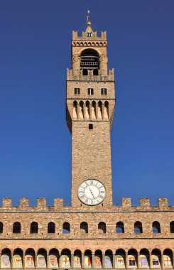 Floransa, İtalya-16 Mayıs 2022: The Palazzo Vecchio-Old Palace veya della Signoria 'dan mavi gökyüzüne yansıyan Torre di Arnolfo Kulesi, MS 1299-1314 Orta Çağ binası XVI c' ye kadar genişletildi..