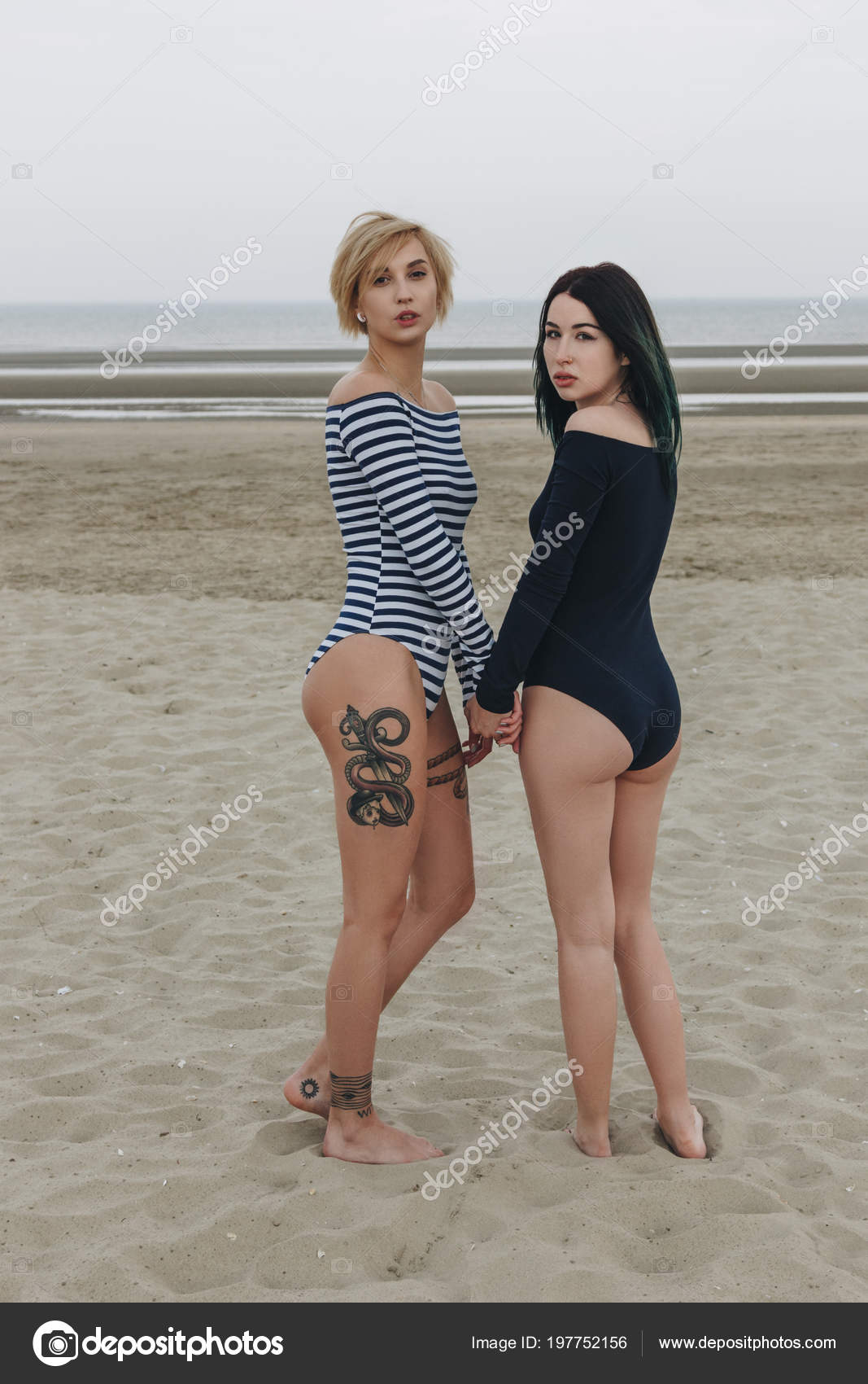 Beautiful Young Women Bodysuits Holding Hands Sandy Beach Looking