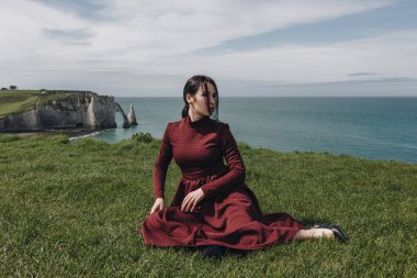 denize sıfır, Etretat, Normandy, Fransa yeşil cliff üzerinde oturan moda kız
