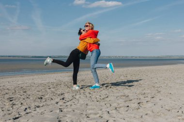 happy friends hugging on sandy beach, Saint michaels mount, Normandy, France clipart