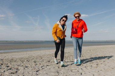 happy girls walking on sandy beach, Saint michaels mount, Normandy, France clipart