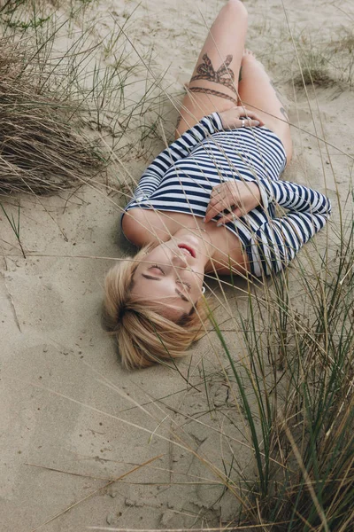 Высокий Угол Обзора Чувственной Молодой Женщины Полосатом Купальнике Лежащей Песке — Бесплатное стоковое фото