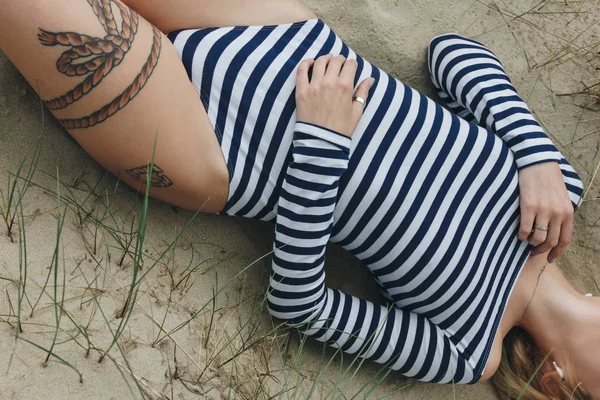 Beskuren Bild Kvinna Randig Bodysuit Liggande Sand — Gratis stockfoto