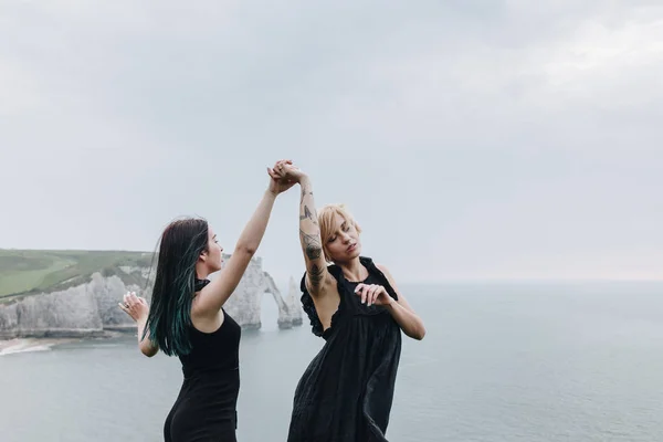 Young Women Holding Hands Cliff Front Ocean Cloudy Day — Free Stock Photo