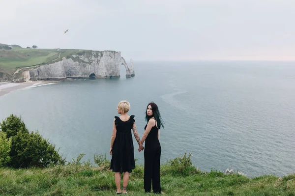 Rear View Young Women Holding Hands Cliff Front Ocean Cloudy — Stock Photo, Image