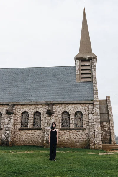 Attraktive Junge Frau Steht Auf Grünem Gras Vor Alter Kirche — kostenloses Stockfoto