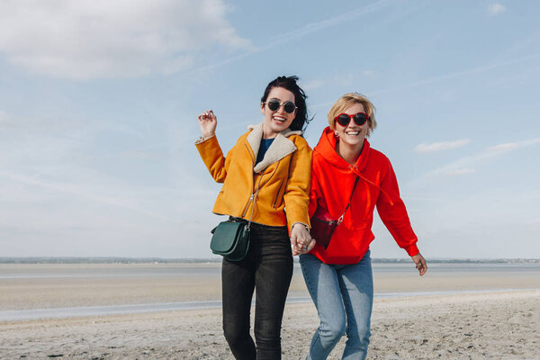 smiling female friends on sandy beach, Saint michaels mount, Normandy, France