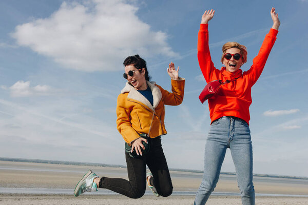 счастливые девушки, прыгающие на песчаном пляже, Saint Michaels Mount, Nordey, Франция
