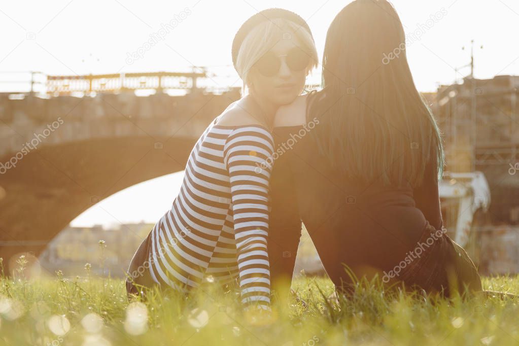 beautiful young women sitting on grass in park on sunset