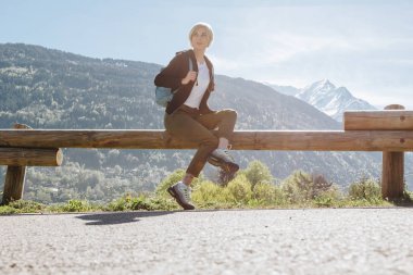 ahşap çit oturan ve uzak dağlar, mont blanc, Alpler'de seyir sırt çantası ile kızın düşük açılı görünüş