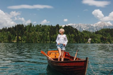 güzel ve genç birbayan tekne sakin dağ Gölü, bled, Slovenya ayakta güneş gözlüğü