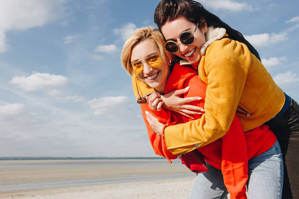 happy girls piggybing on sandy beach, Saint Michaels Mount, Norfely, France
