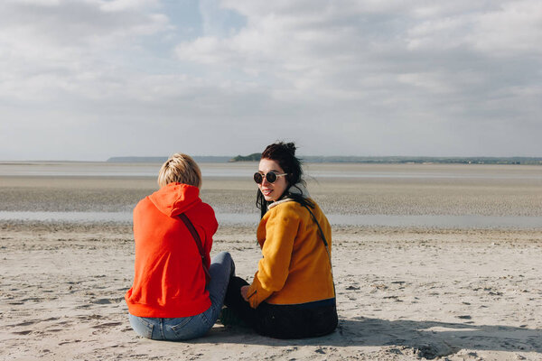 rear view of tourists sitting on sandy beach, Saint michaels mount, Normandy, France