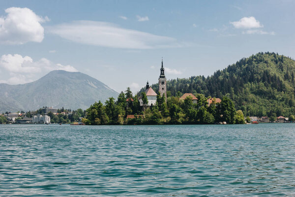 old architecture and green trees at bank on scenic mountain lake, bled, slovenia