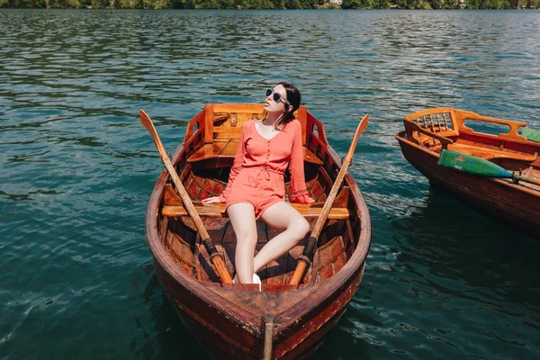 Beautiful girl in sunglasses sitting on wooden boat on lake — Stock Image Beautiful Girl Sunglasses Sitting Wooden Boat Lake Stock Photo