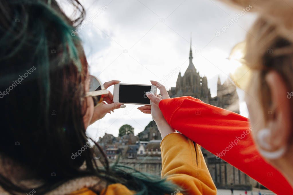 cropped view of tourists taking photo of Saint michaels mount on smartphone, Normandy, France