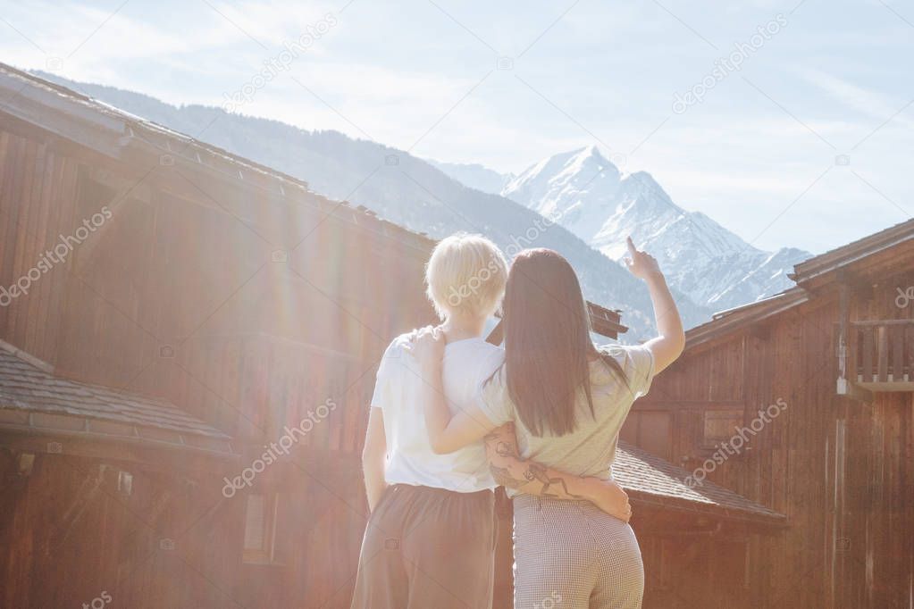 back view of young women embracing and looking at majestic mountains, mont blanc, alps