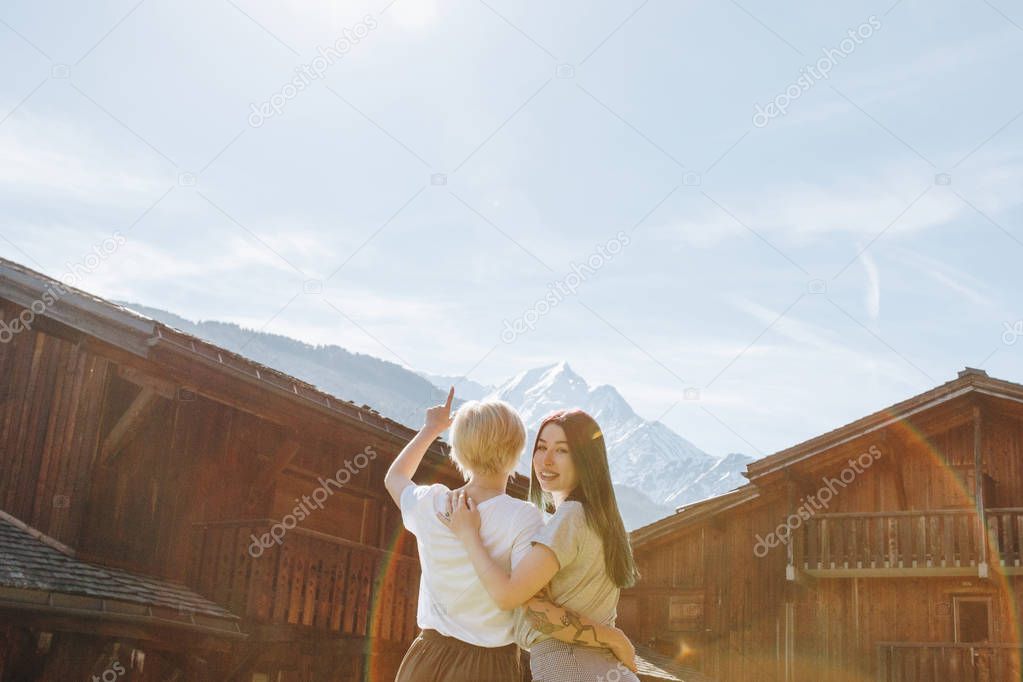back view of young girlfriends embracing and looking at beautiful mountains, mont blanc, alps