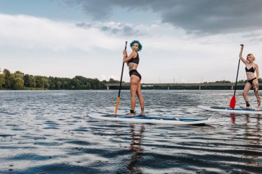 paddleboards Nehri üzerinde sörf atletik dövmeli kadın