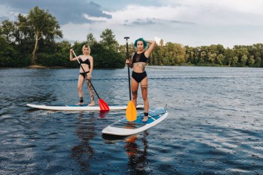atletik dövmeli kadın standup paddleboarding Nehri üzerinde