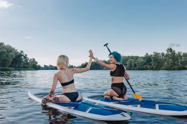 Athletic Women Giving Highfive While Sitting Paddle Boards River — Stock Photo, Image