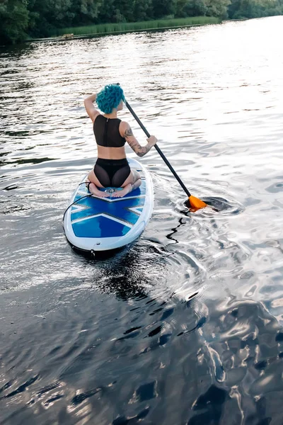 Achteraanzicht Van Sportieve Meisje Met Blauwe Haren Paddle Surfen Rivier — Gratis stockfoto