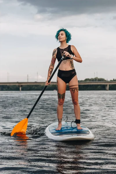 Hermosa Chica Tatuada Deportiva Con Pelo Azul Paddle Boarding Río — Foto de stock gratis