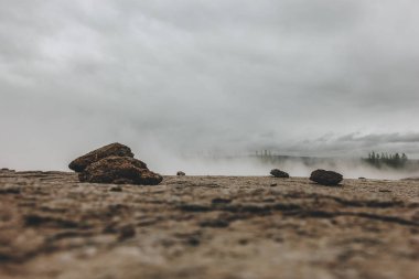 yüzey ile peyzaj taşlar ve İzlanda'daki Haukadalur Vadisi'nde bulutlu gökyüzü altında buhar