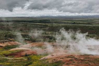 aerial view landscape with volcanic vents under cloudy sky in Haukadalur valley in Iceland clipart