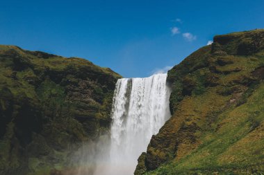 şelale Skogafoss mavi gökyüzünde parlak: İzlanda karşı doğal görünümü