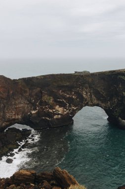 kayalık uçurum ve okyanus Dyrholaey promontory Vik, İzlanda, bulutlu gökyüzü altında doğal görünümünü