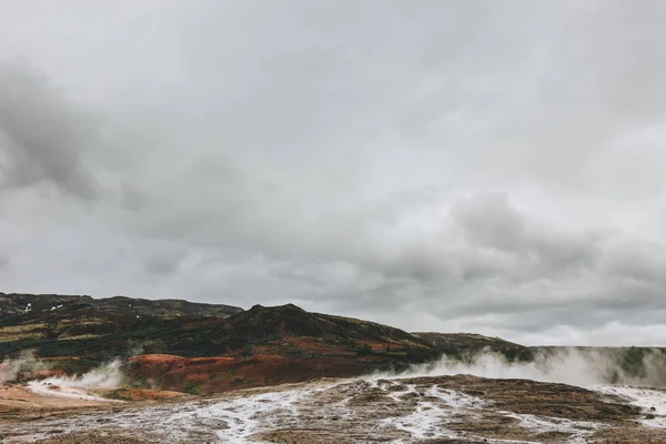 アイスランドの Haukadalur 渓谷の曇り空の下で火山の通気孔のある風景の眺望  — 無料ストックフォト