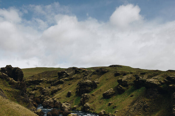 cloudy blue sky and beautiful mountain river flowing through highlands in Iceland