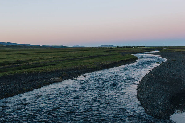 scenic view of landscape with river flowing near meadow in Iceland
