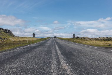 Highlands İzlanda'daki mavi bulutlu gökyüzü altında araba ile yol 