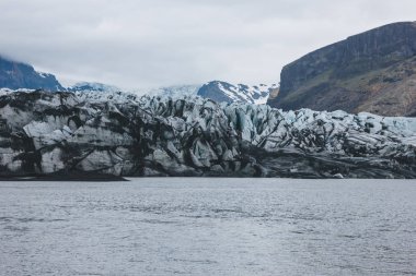 glacier Skaftafellsjkull and snowy mountains against cloudy sky in Skaftafell National Park in Iceland  clipart