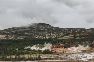İzlanda - 20 Haziran 2018: turist Haukadalur Vadisi'nde volkanik bacalar yakınındaki uzak görünümü