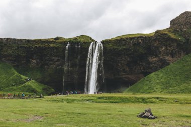 İzlanda - 20 Haziran 2018: güzel şelale Seljalandsfoss ve turistler bulutlu gökyüzü altında 