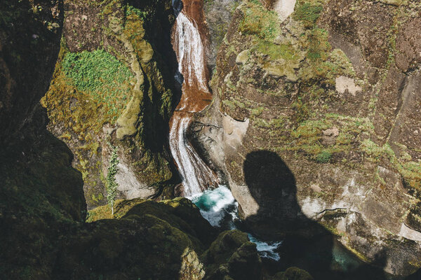 aerial view of river flowing down from mountain with sunlight in Fjadrargljufur Canyon in Iceland