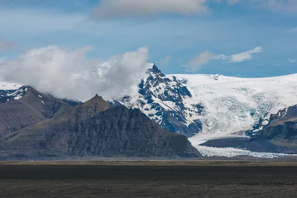 beautiful landscape with mountains covered by snow under blue cloudy sky in Iceland
