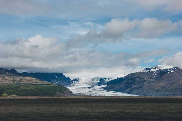 scenic view of landscape with mountains covered by snow under cloudy sky in Iceland