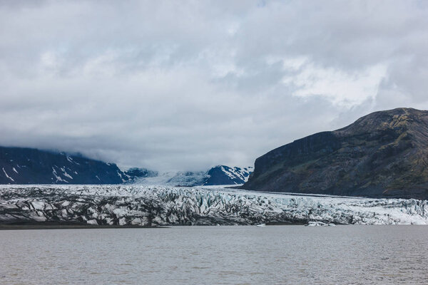 scenic view of glacier Skaftafellsjkull and snowy mountains against cloudy sky in Skaftafell National Park in Iceland 