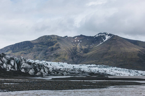 glacier Skaftafellsjkull and snowy mountains against cloudy sky in Skaftafell National Park in Iceland 